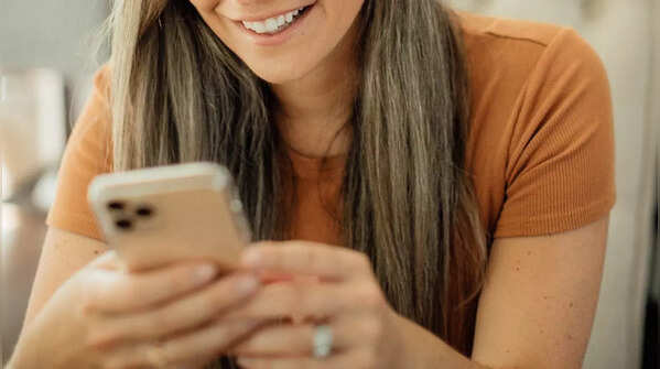 Holding phone with both hands, scrolling with one thumb.